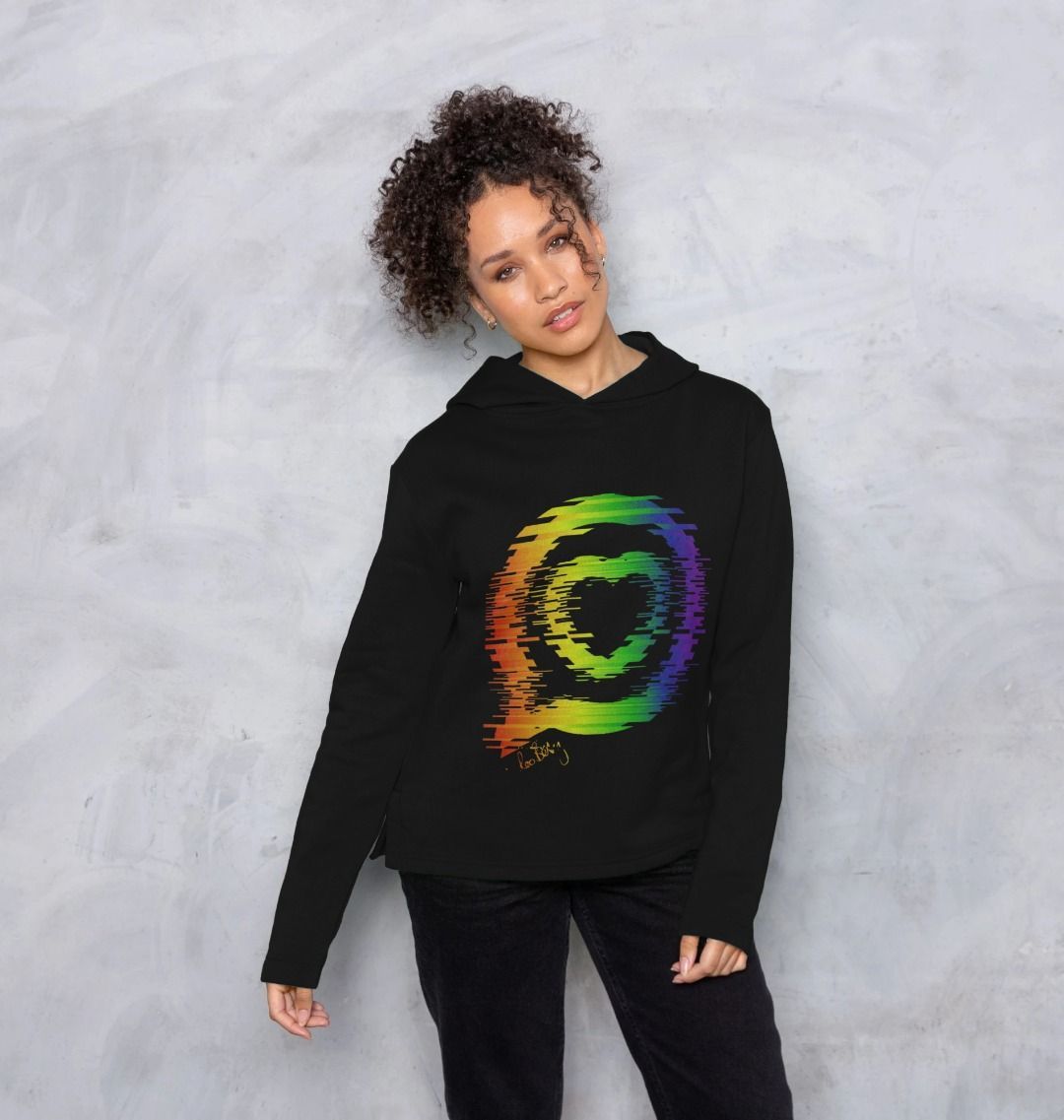 Woman wears relaxed fit black hooded top with the roo betty logo in "torn" rainbow design 