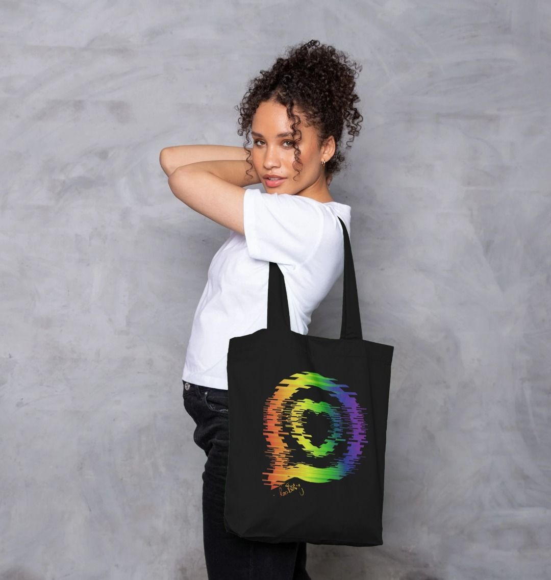 Model wear white t-shirt and carries a small black tote bag with the Roo Betty Logo in the torn rainbow print