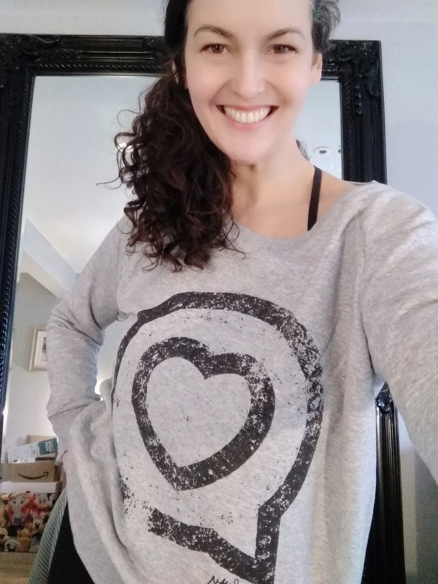 Ruth wears an organic cotton sweatshirt with the Roo Betty logo of a heart in a speech bubble in a vintage style print