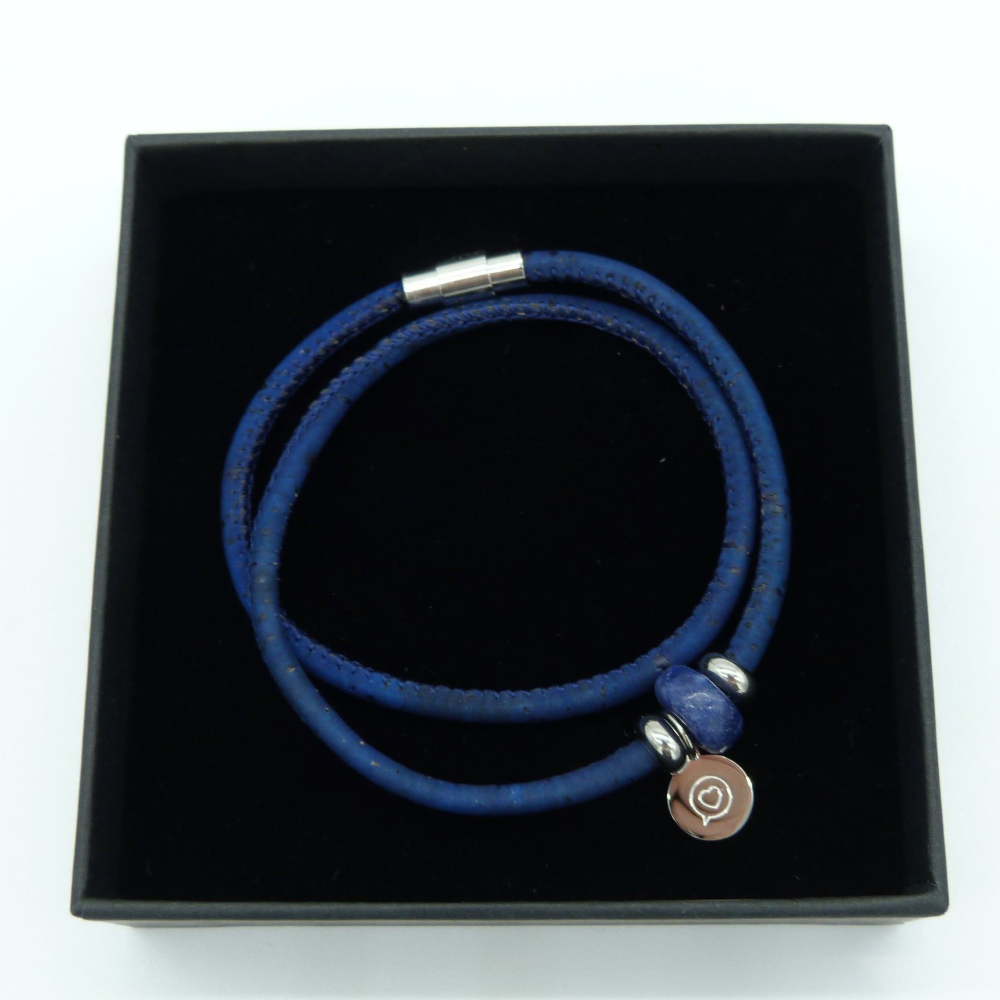 Blue cork bracelet with stainless steel magnetic clasp . Gemstone Sodalite bead with stainless steel tag with the logo of Roo Betty of a heart in a speech bubble . Presented in a black gift box