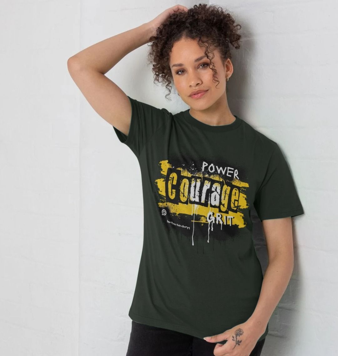female model wears the unisex dark grey t-shirt from the words to emower collection in the solar plexus energy design of bright yellow paint splash and the words power courage grit in a bold font 